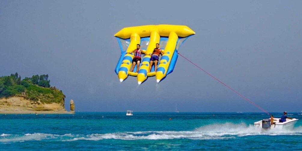 Two people parasailing over a body of water with a boat in the background. 1