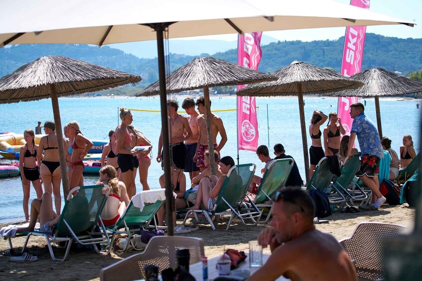 A beach with people sunbathing, umbrellas, and flags. 4