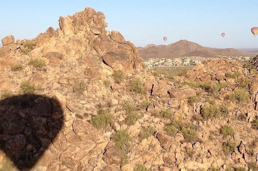 A rocky desert landscape with scattered vegetation and distant hills. 2