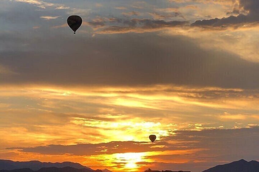 A hot air balloon over a sunset with mountains in the background. 3
