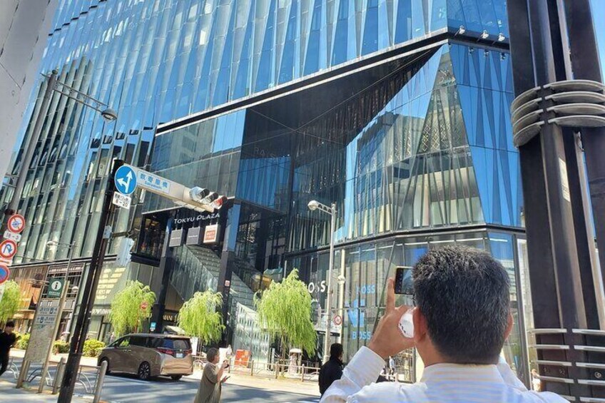 A modern glass building with signage for 'TOKYU PLAZA' and a pedestrian crossing sign. 3