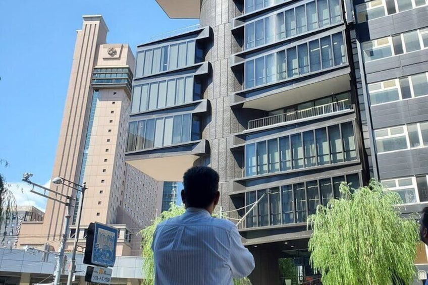 A man taking a photo of a modern building with multiple floors and balconies. 2