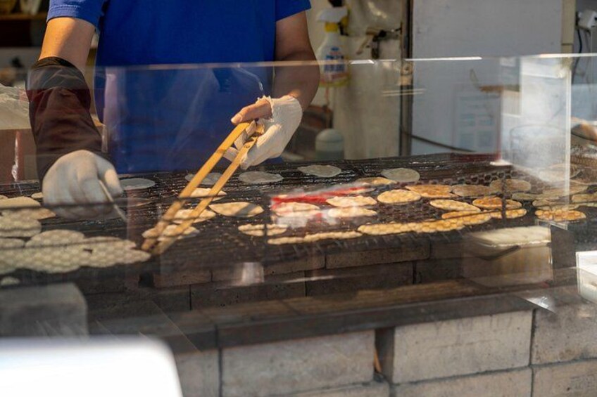 A person cooking on a griddle with various food items. 4