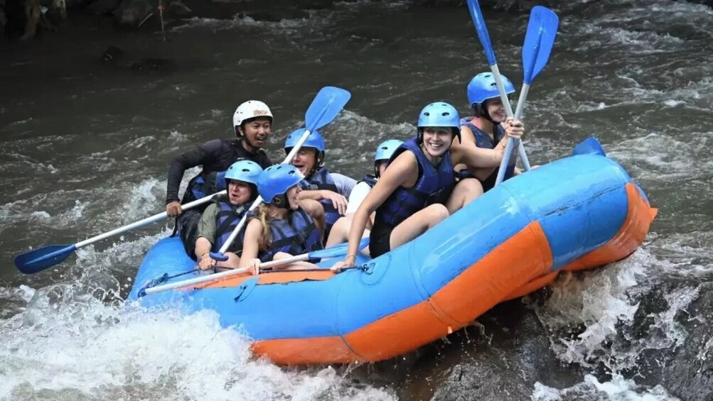 A group of people in a blue and orange raft navigating a river. 4