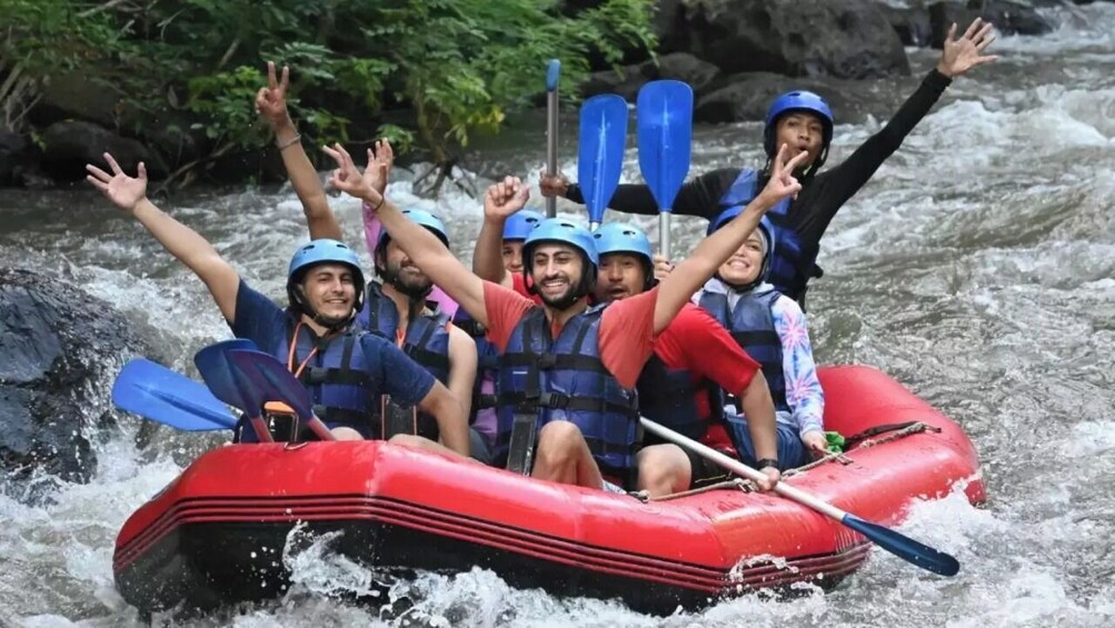 A group of people in a red inflatable raft on a river with rapids. 3