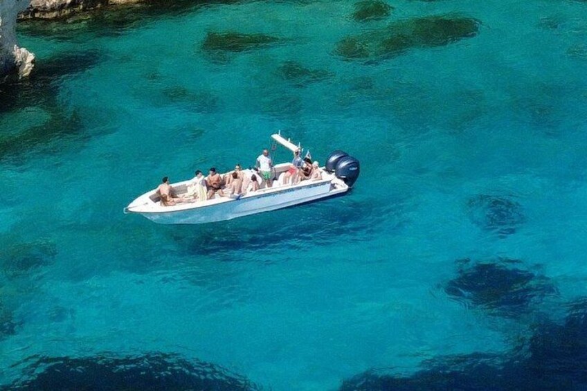 A small motorboat with several people on a clear blue sea. 5