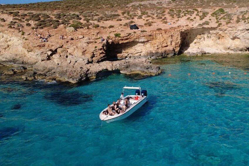A boat on clear turquoise water near rocky cliffs. 2