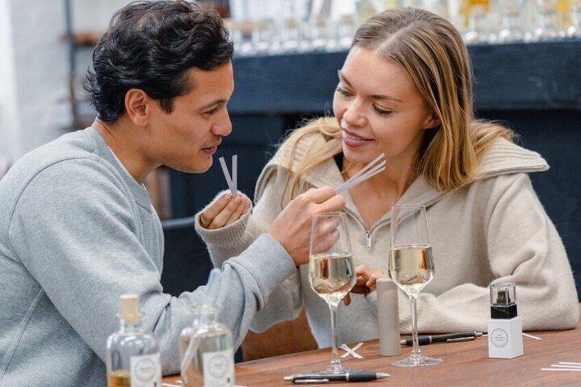 Two people sitting at a table with wine glasses and bottles. 2