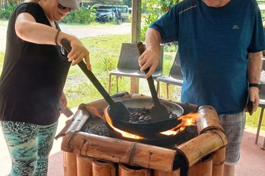 Two people cooking outdoors using a traditional stove with a pot and a fire. 2