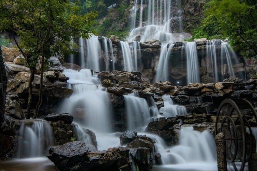 A multi-tiered waterfall with a wooden wheel structure. 3