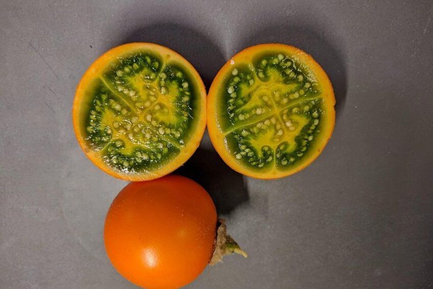 A halved tomato with seeds and a whole tomato on a gray surface. 4