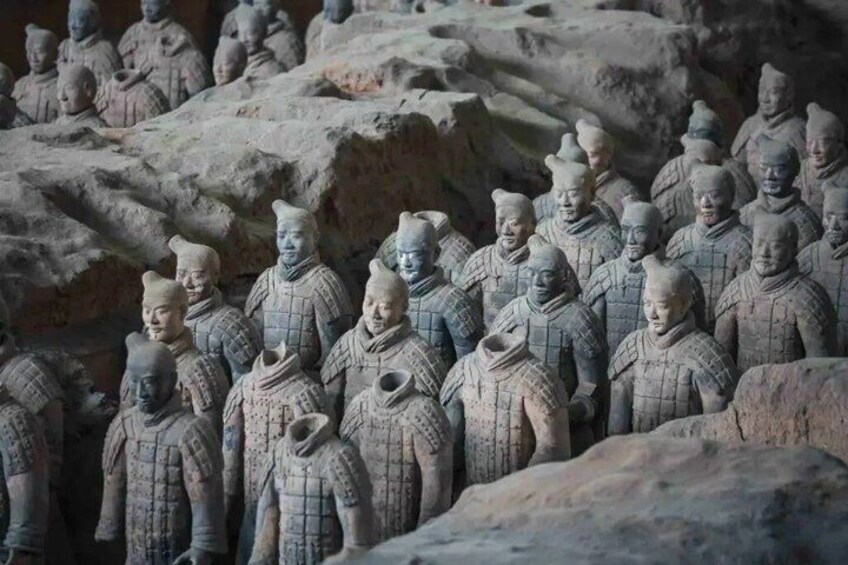 Terracotta soldiers in a row, standing on a rocky terrain. 3