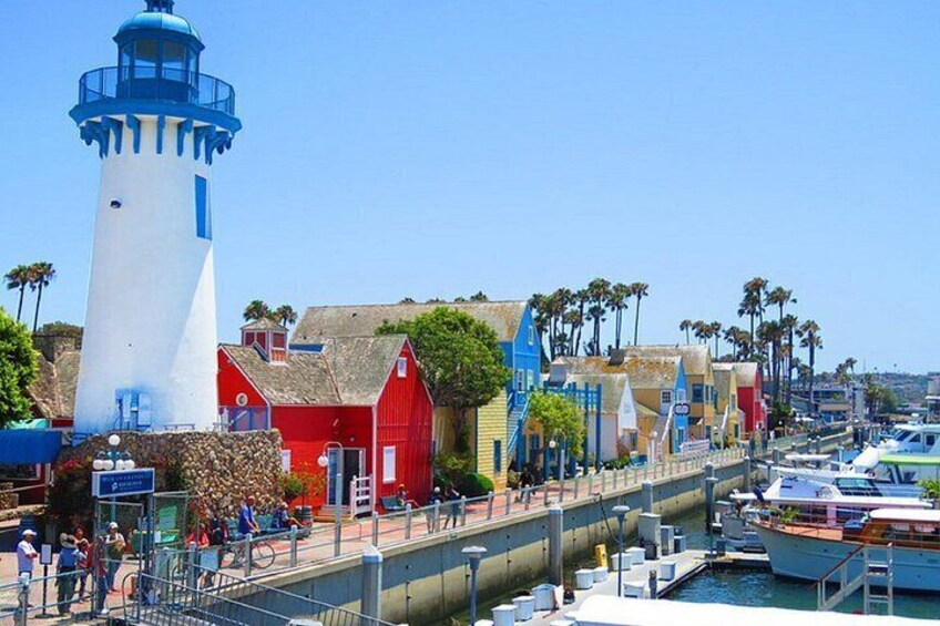 A coastal town with a prominent white lighthouse, colorful buildings, and a marina with boats. 4