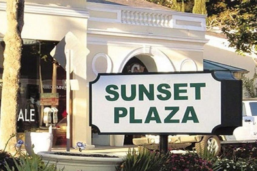 A sign for Sunset Plaza with a building in the background. 3