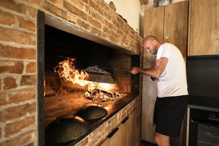 A person opening a brick oven with flames visible inside. 2