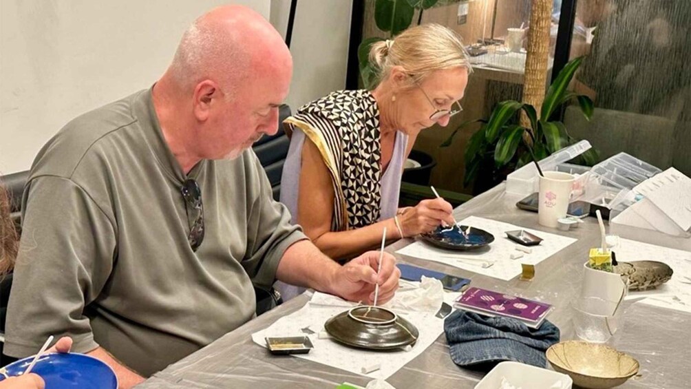 Two people engaged in a pottery activity at a table with various pottery tools and materials. 2