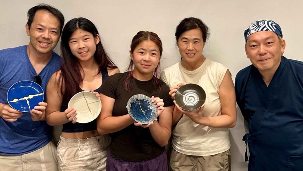Five people holding plates with designs. 4