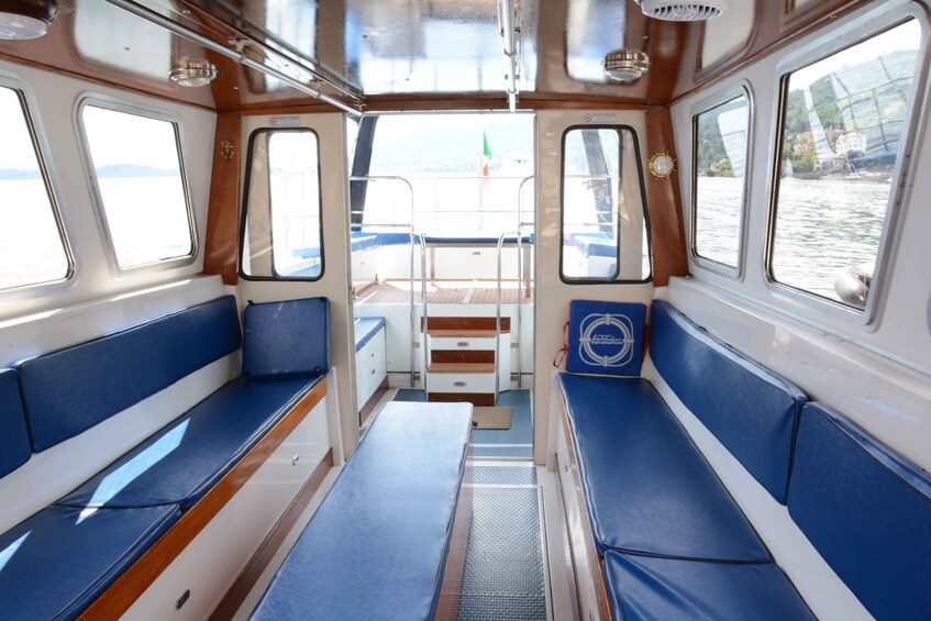 A boat cabin with blue cushioned benches, a central table, and windows with a view of the water. 2