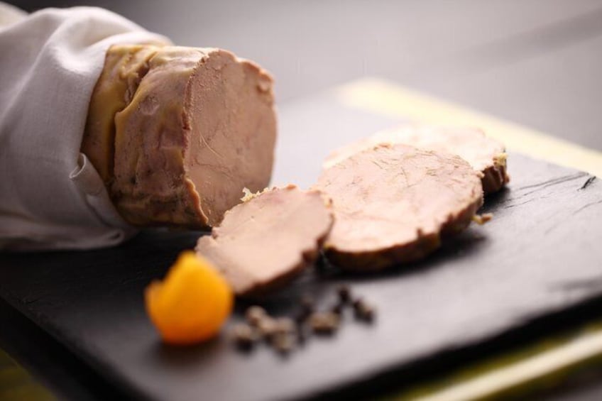 A sliced roast beef on a dark slate plate with a cloth and a small orange fruit. 5