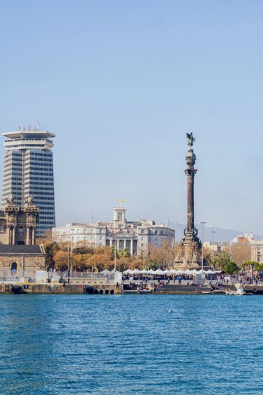 A cityscape with a prominent statue, a modern skyscraper, and a waterfront. 3