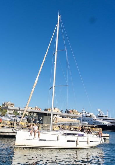 A sailboat docked at a marina with other boats and buildings in the background. 4