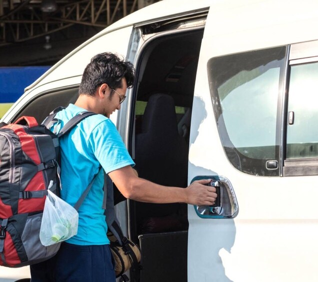 A person with a backpack exiting a white van. 4