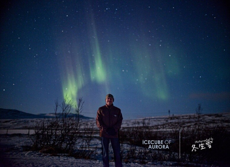 A person standing in a snowy landscape under a night sky with aurora borealis. 4