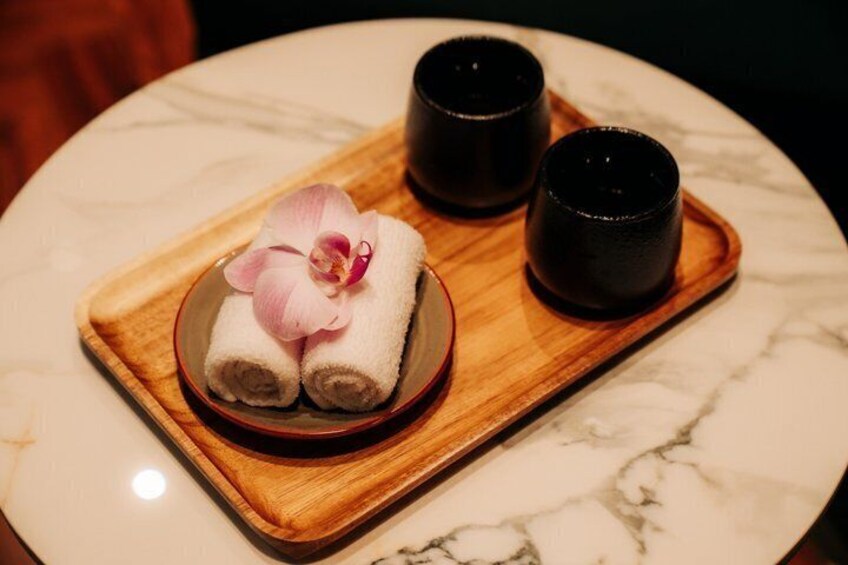 A tray with towels and a flower, two black cups, and a marble surface. 3