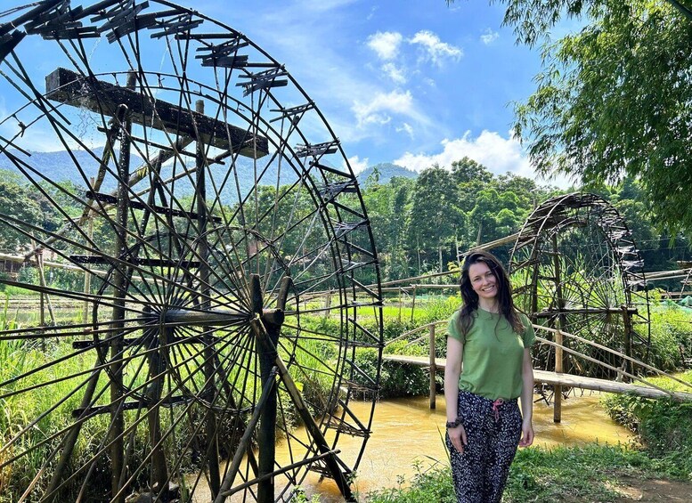 A large water wheel in a rural setting with lush greenery and a clear sky. 5