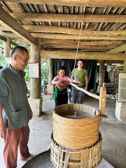 A traditional rice pounding process with a large wooden mortar and pestle. 3