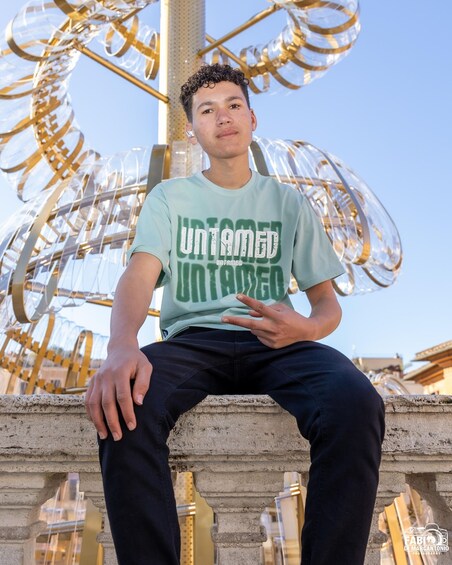 A person sitting on a stone bench with a large, abstract sculpture in the background. 5