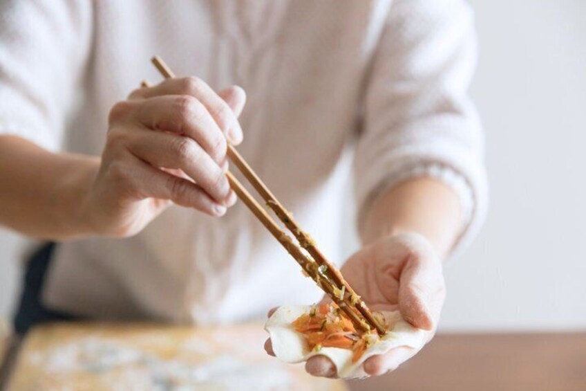 A person holding chopsticks over a bowl of food. 1