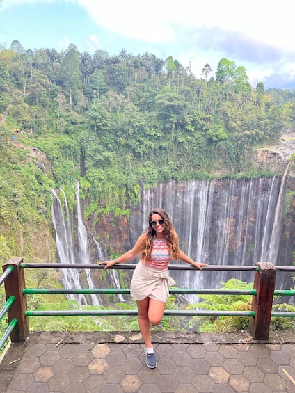 A person standing by a waterfall with lush greenery in the background. 3