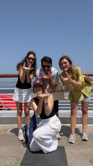 A group of people posing on a deck with a railing and a view of the sea. 1