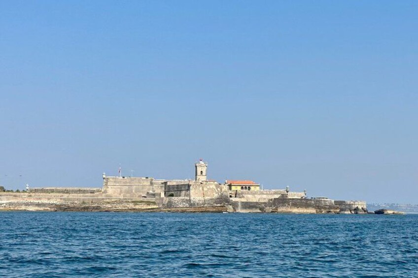 A coastal fortification with a prominent tower and a lighthouse, surrounded by water. 3