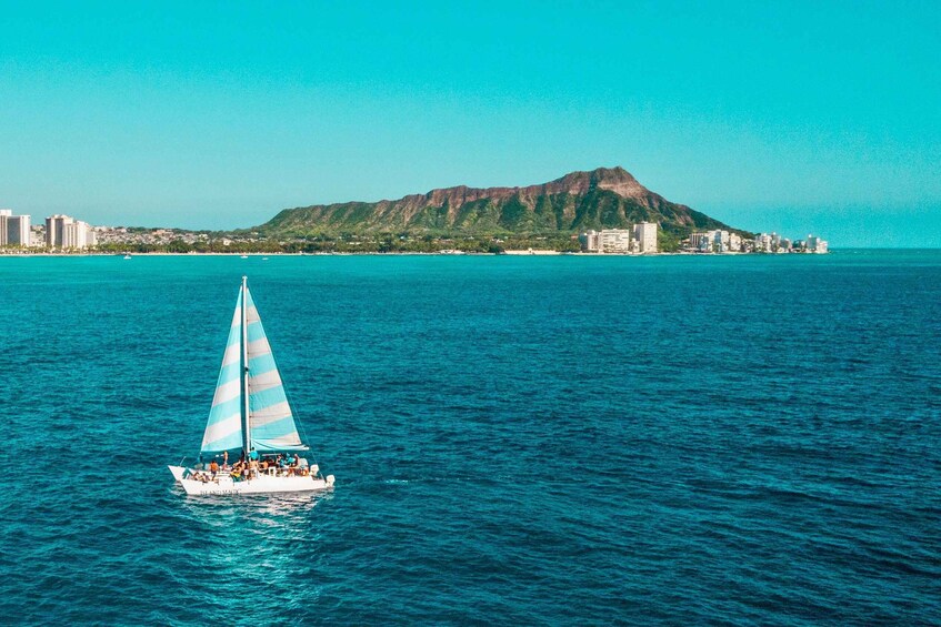 A sailboat on turquoise waters with a mountain in the background. 4