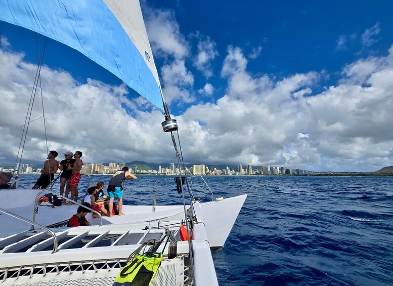 A sailboat with people on deck, a city skyline in the background, and a partly cloudy sky. 2