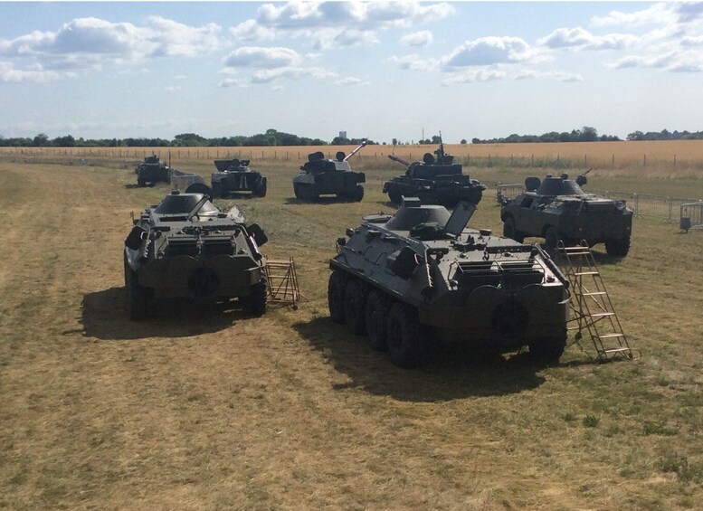 Military tanks lined up in a field with a clear sky. 4
