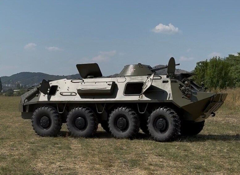A military vehicle with six wheels, a mounted gun, and a satellite dish on a grassy field. 5