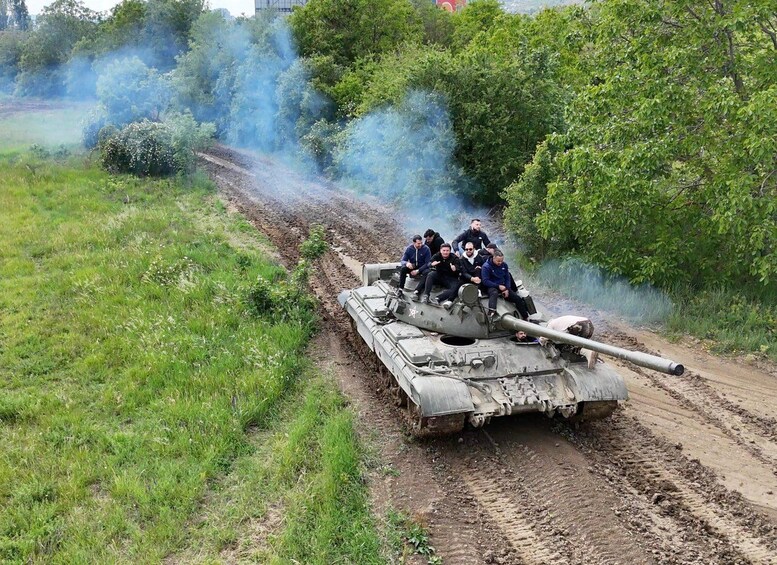 A military tank on a dirt road with smoke in the background. 1