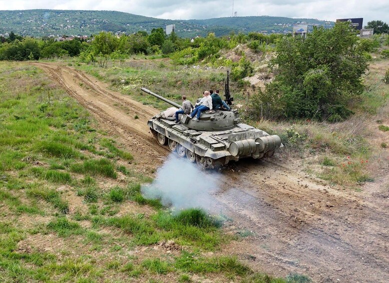 A military tank on a dirt road with smoke coming from its rear. 2