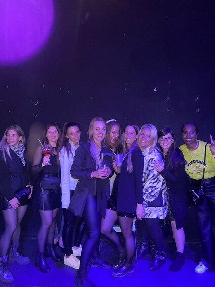 A group of people posing together at an event with purple lighting. 5