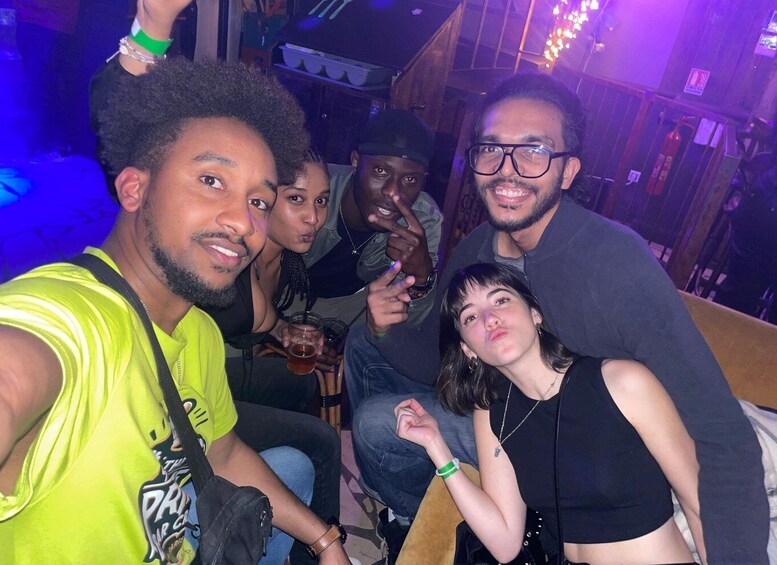 A group of people in a dimly lit indoor setting with purple lighting. 2
