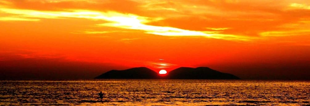 A sunset over a body of water with mountains in the background. 5