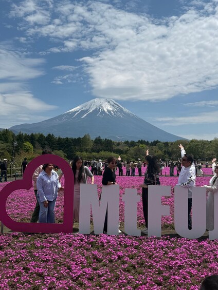Un grupo de personas posa frente a un gran letrero de 'MIFU', con una montaña al fondo. 4