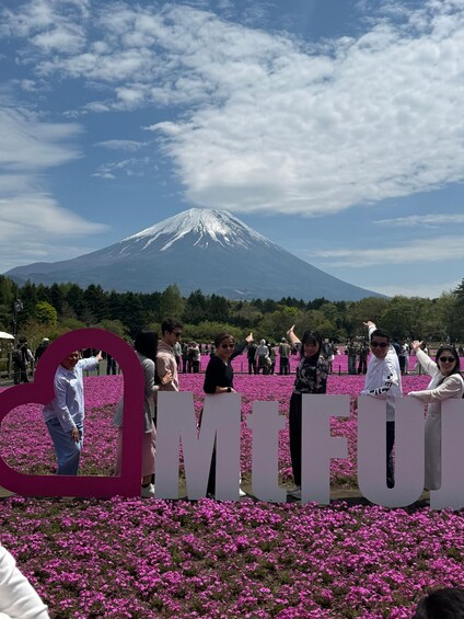 Un grupo de personas frente a un gran letrero con las letras 'MIFU' y una montaña al fondo. 5