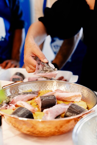 Henkilö pitää ruokapalaa kulhon yläpuolella, ja kulhossa on erilaisia ruoka-aineita. 3