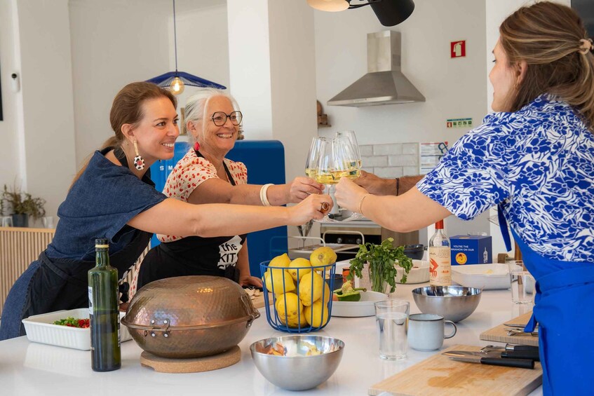 Ryhmä ihmisiä kohottaa viinilasejaan modernissa keittiössä. 4