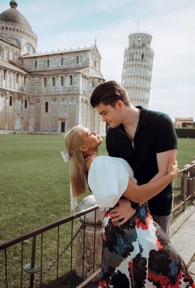 A couple embracing in front of the Leaning Tower of Pisa, with the Pisa Cathedral in the background. 1