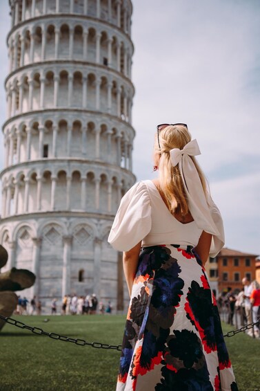 A person with a ponytail standing in front of the Leaning Tower of Pisa. 2